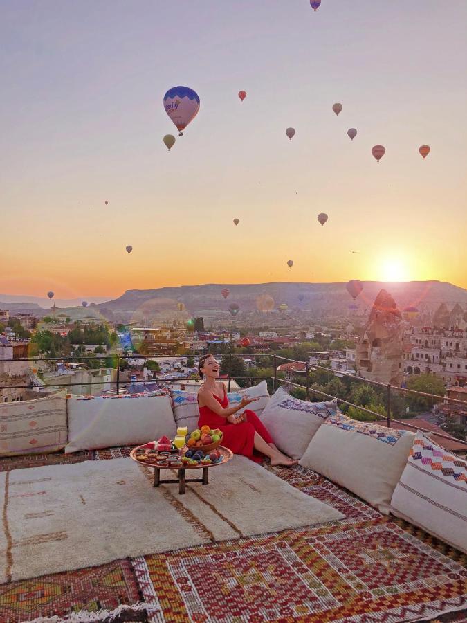 A woman admires hot air balloons from a rooftop terrace in Cappadocia