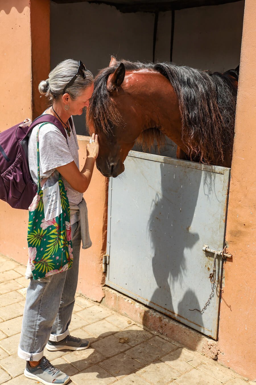 A woman pats at horse at Yassine Cavalier Stables in Diabat, Morocco