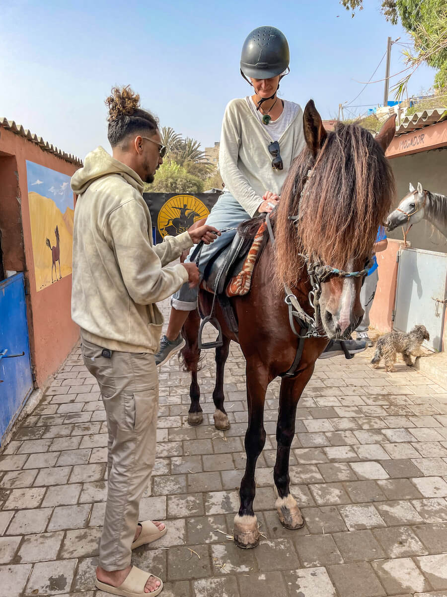 A woman gets horse riding tips from Yassine Cavalier in Essaouira Morocco