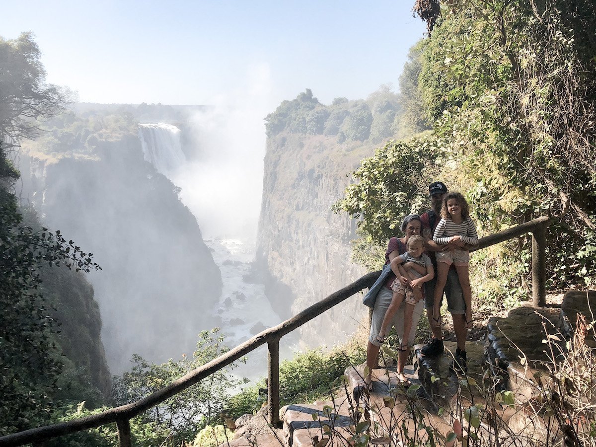 A family on holiday in Victoria Falls stand near the Devils Cataract surrounded by water spray from the waterfall