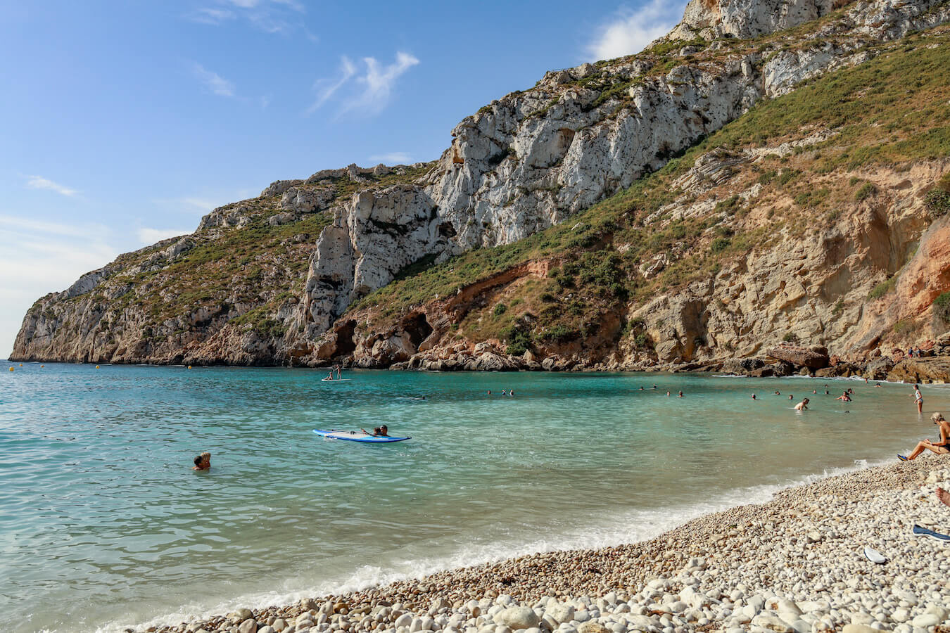 Holidaymakers enjoy the beautiful Granadella Beach in Javea, Spain.