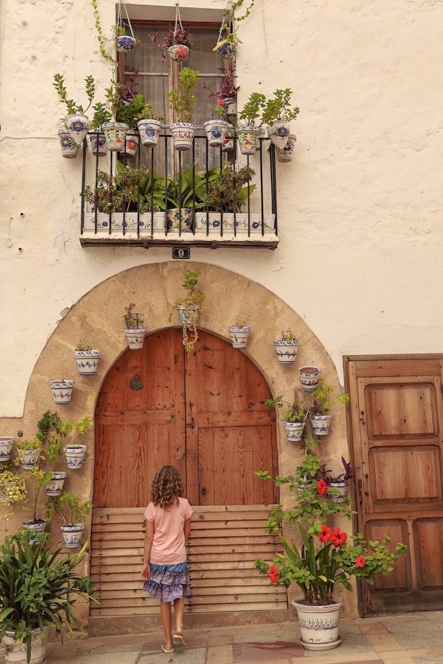 A young girl on holiday in Javea, Spain, admires a decorated doorway in the Historic Centre.