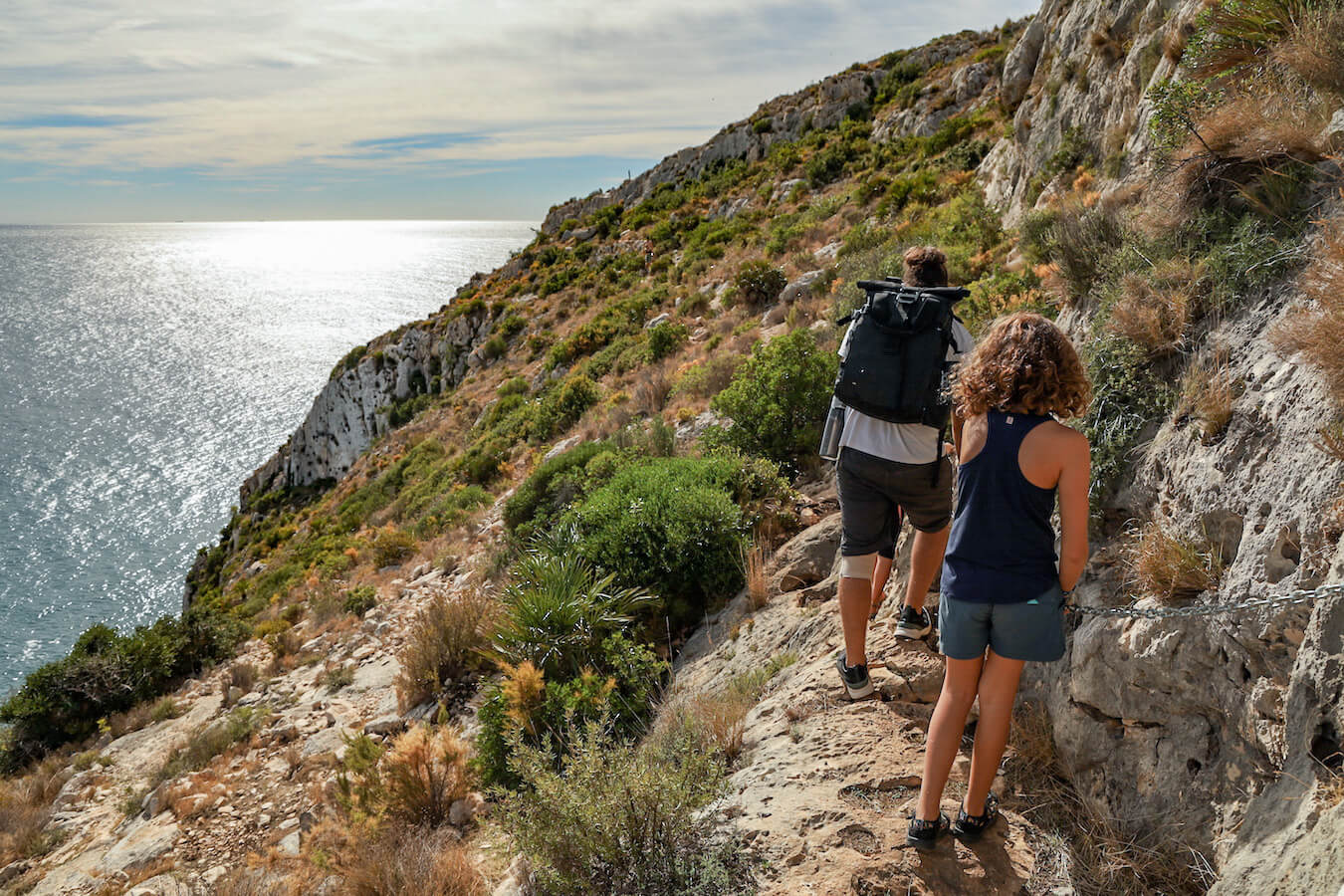 A family hold a chain railing on the PR CV-354 Granadella walk in Javea.