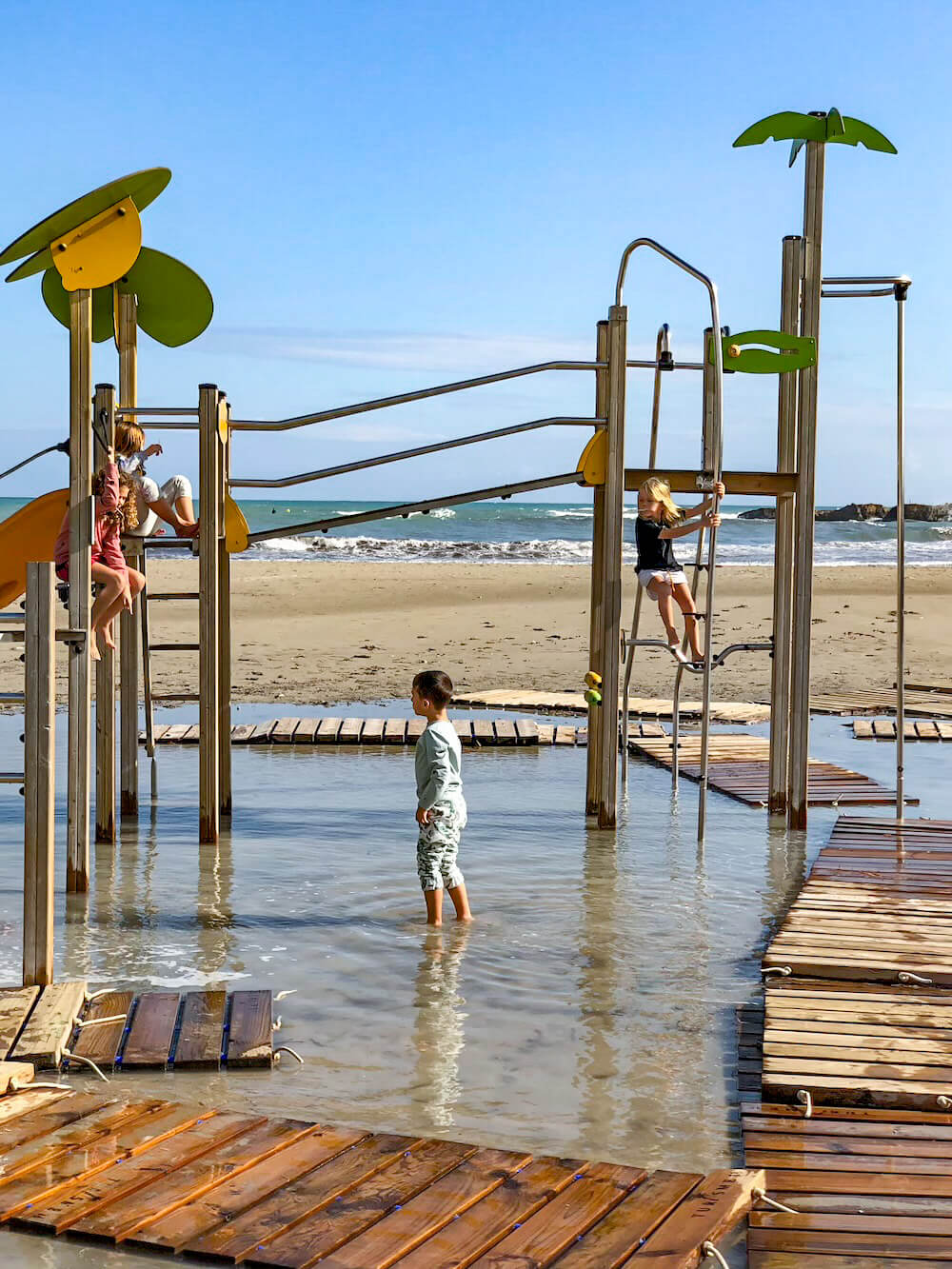 Kids climb the flooded beach play equipment after a heavy rain.