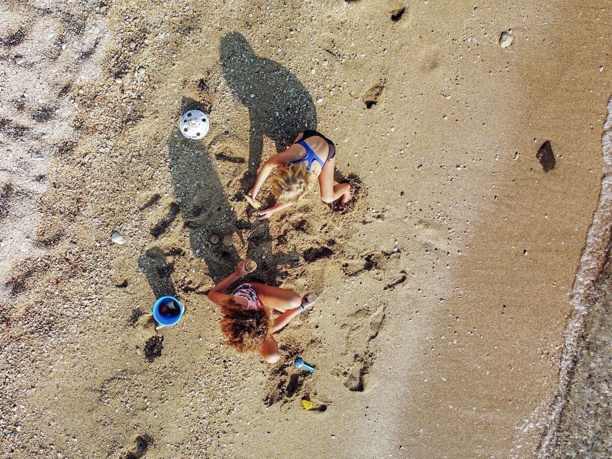 Kids play with sand pit toys on the beach in Javea - drone image.