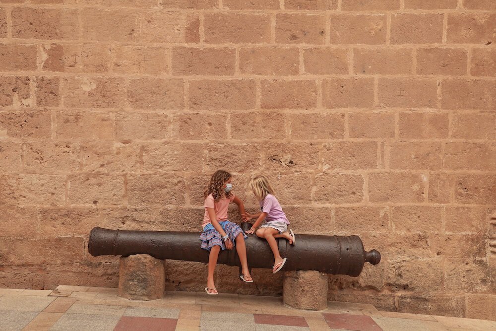 Two kids sit on a canon outside the Bartholomew Church in the Historic Centre of Javea
