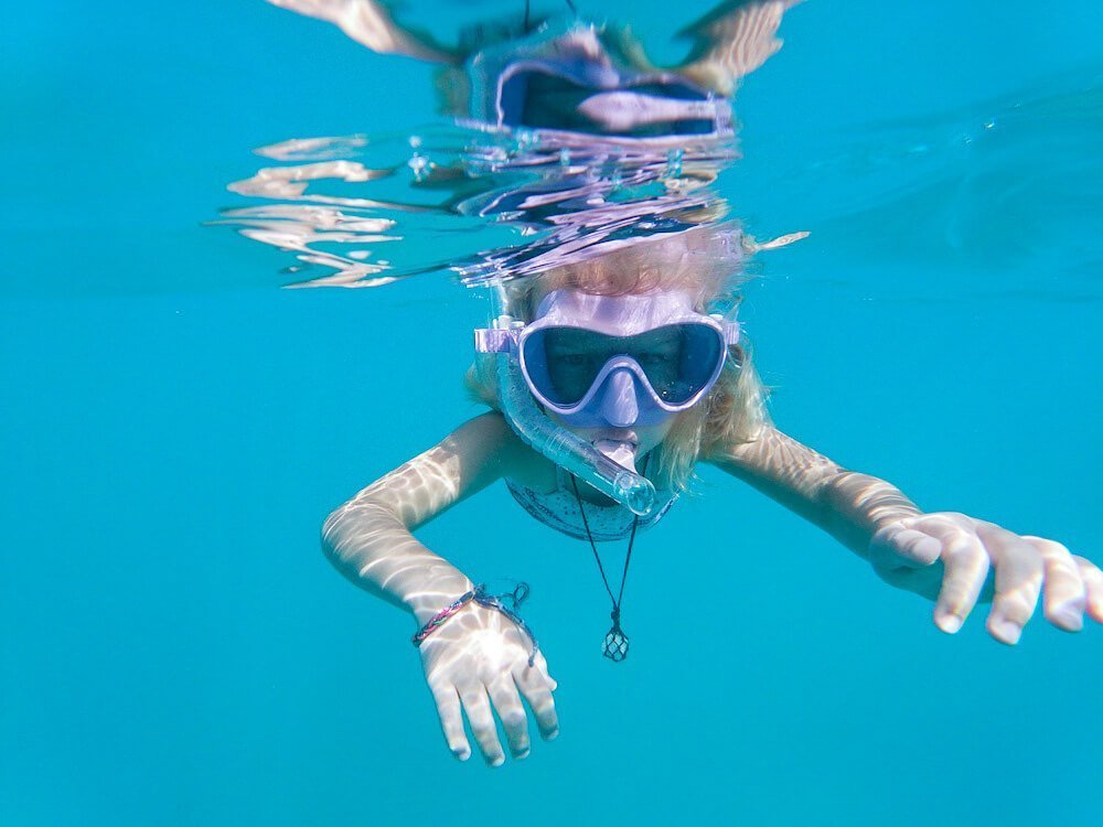 A child on holiday in Javea, swims at Granadella beach with snorkel and mask.