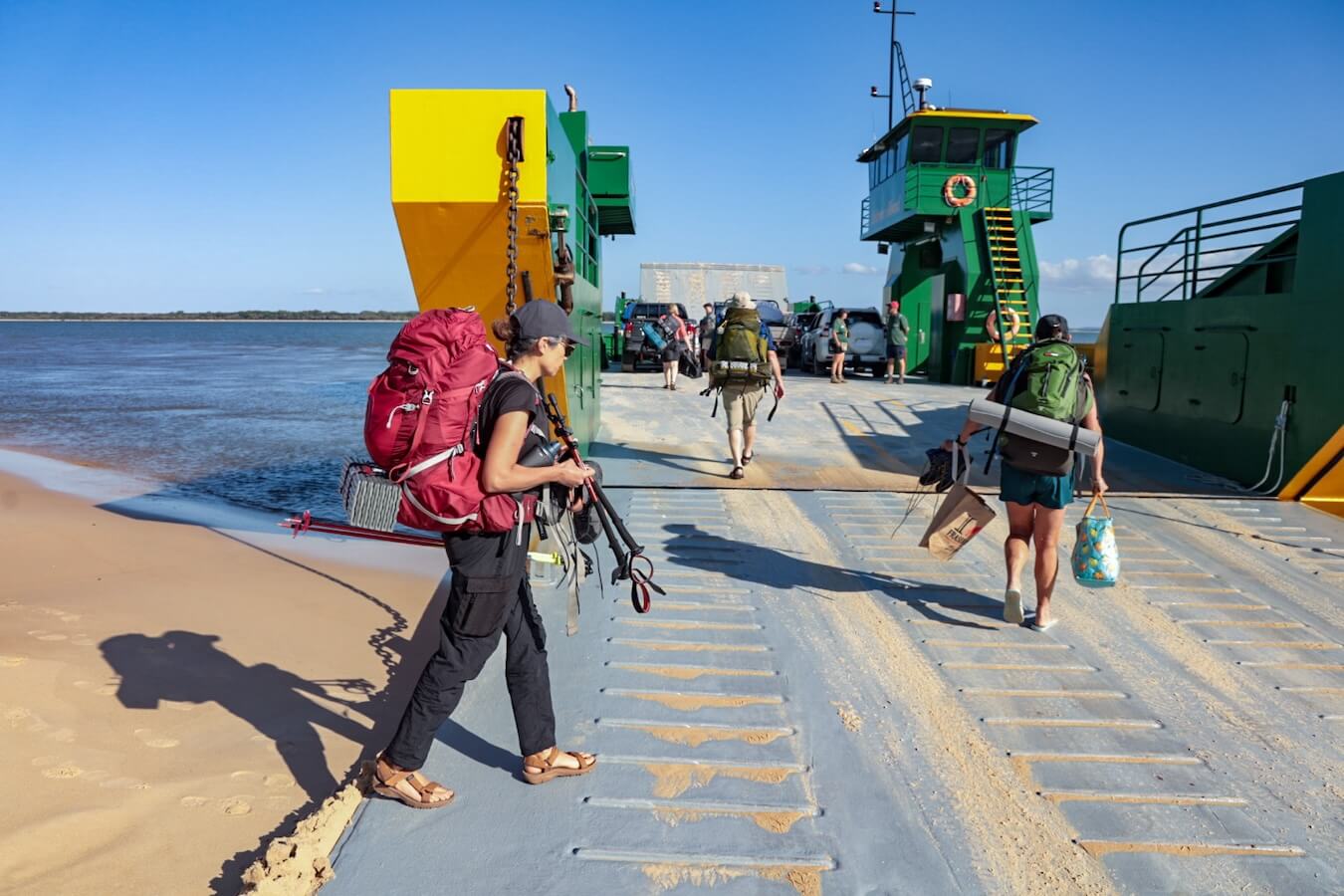 Hikers walk with their backpacks onto the Mantaray Barge at Hook Point on K'gari, Fraser Island