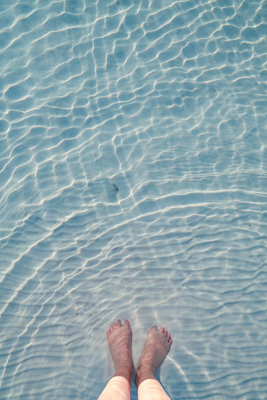 A person's feet standing in the clear fresh water of Lake Boorangora, (Lake McKenzie) on K'gari (Fraser Island)
