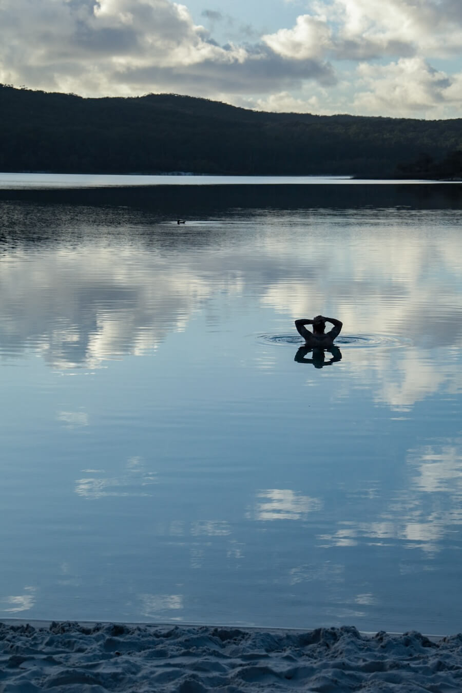 A man swims at Lake McKenzie early in the morning.