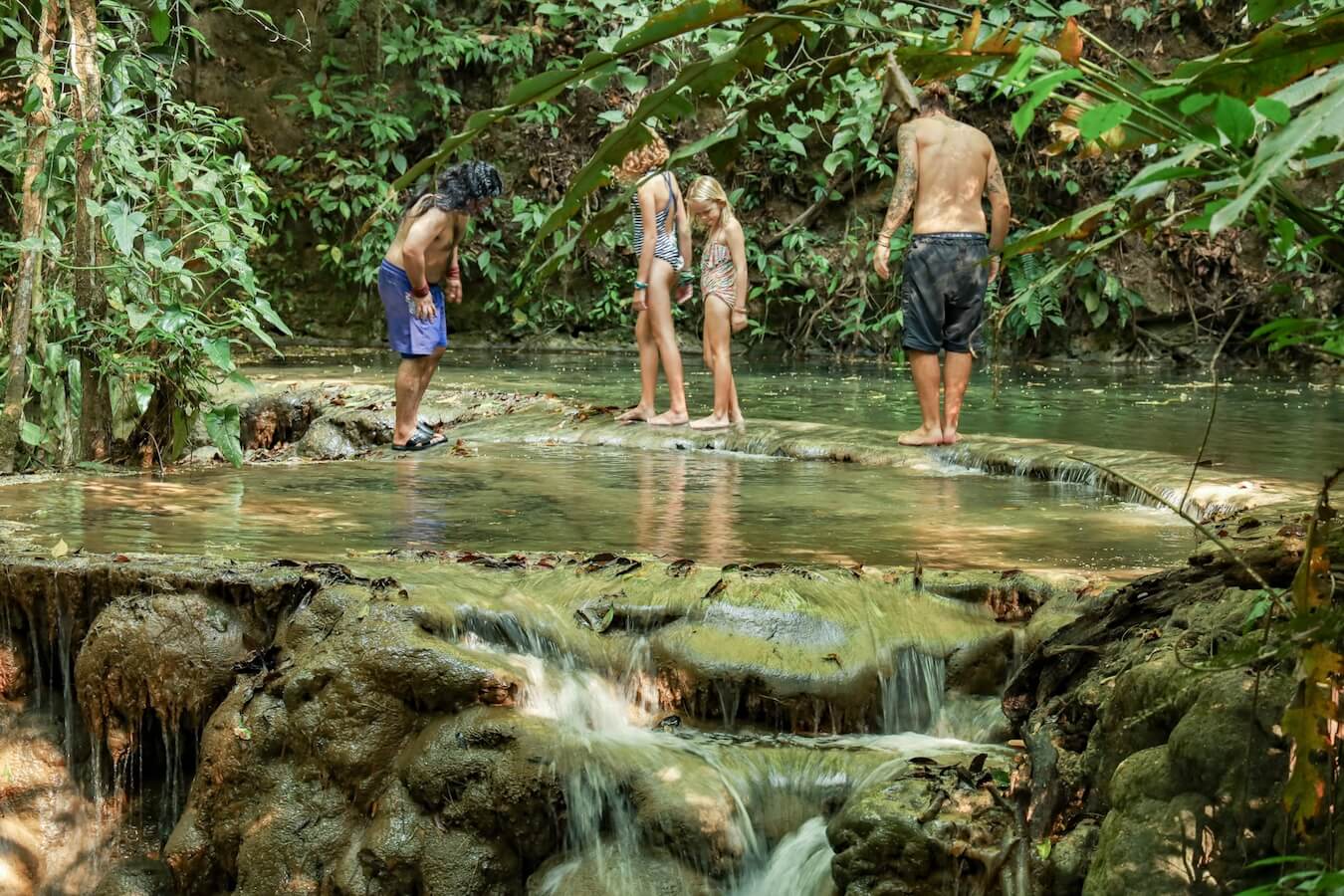 A family walking over waterfalls on a guided tour through the Lacandon Jungle, Mexico