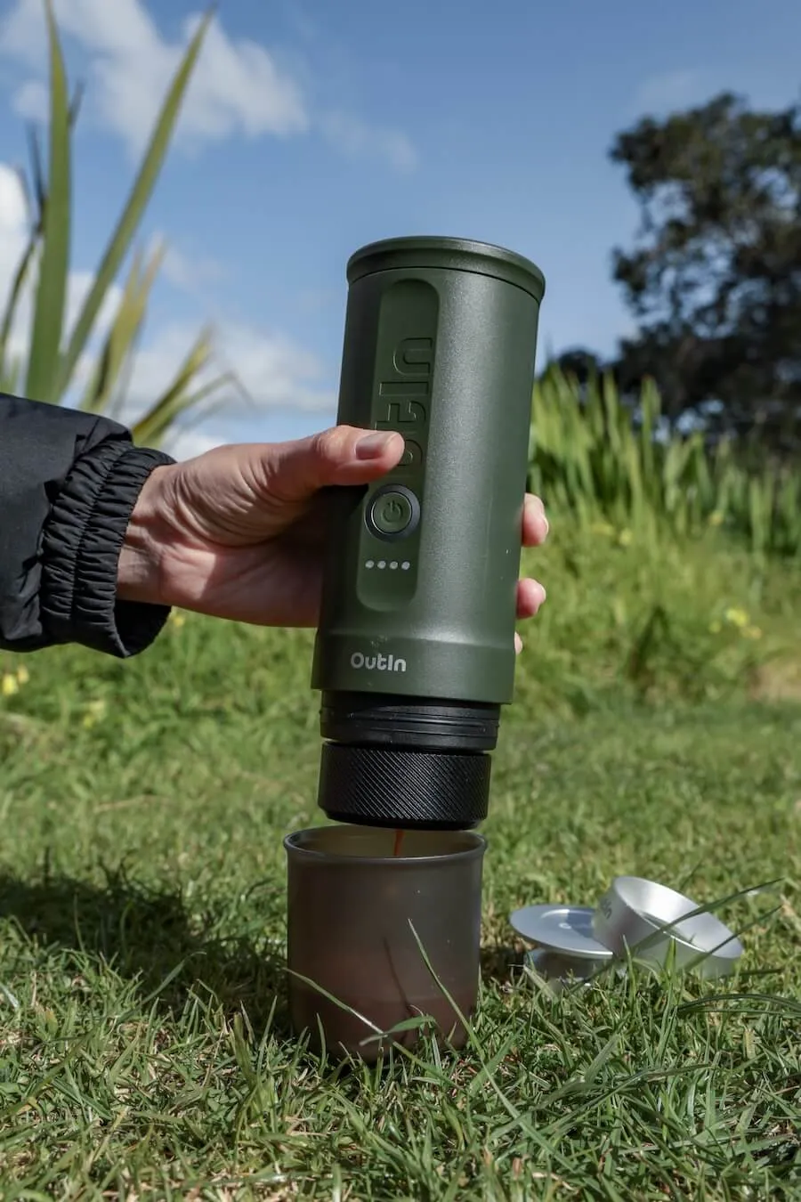 A person makes an espresso with the OutIn automatic portable coffee maker while camping.