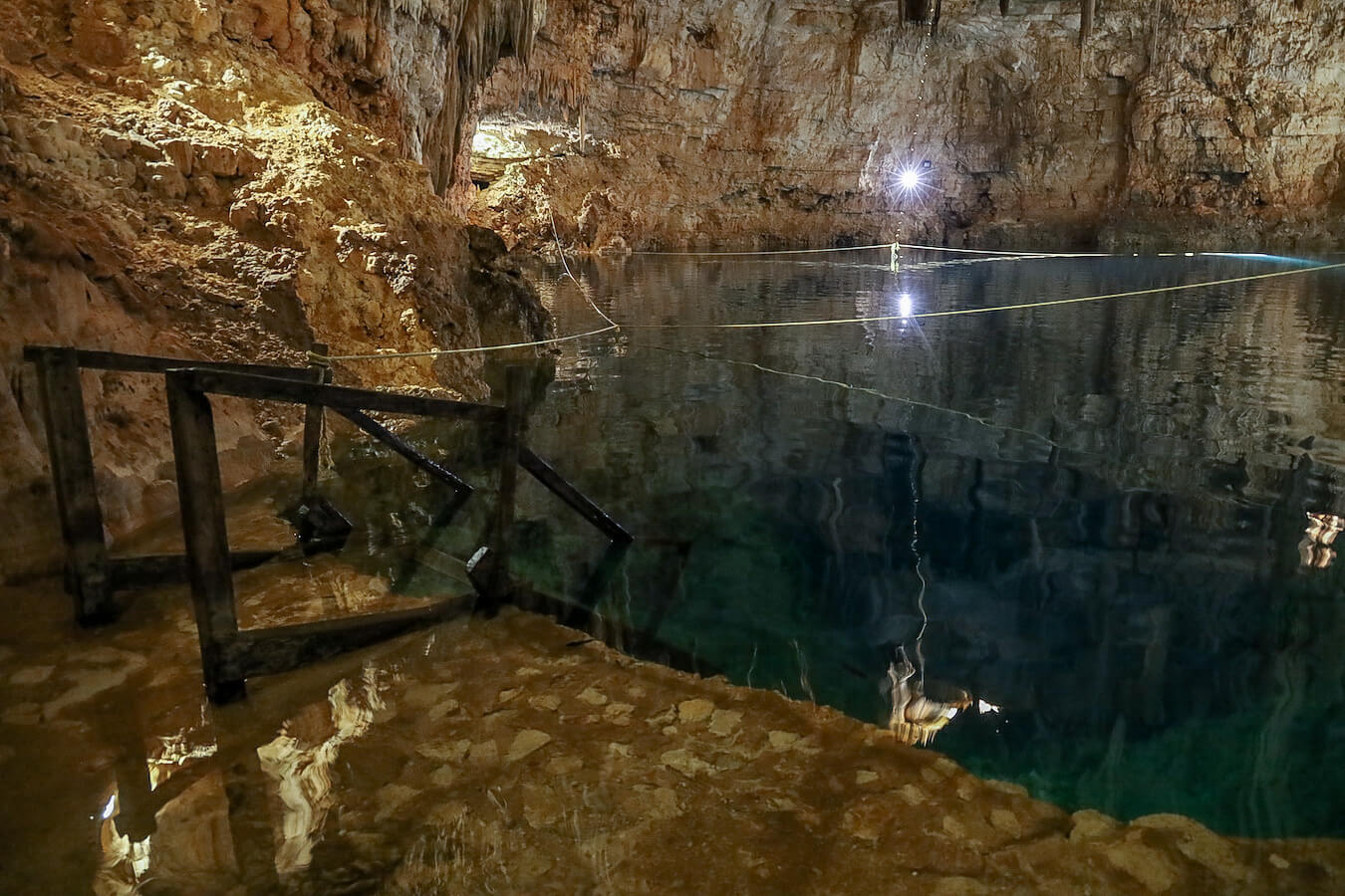 The cavernous Palomitas Cenote without tourists, with spotlights and impressive stalactites.