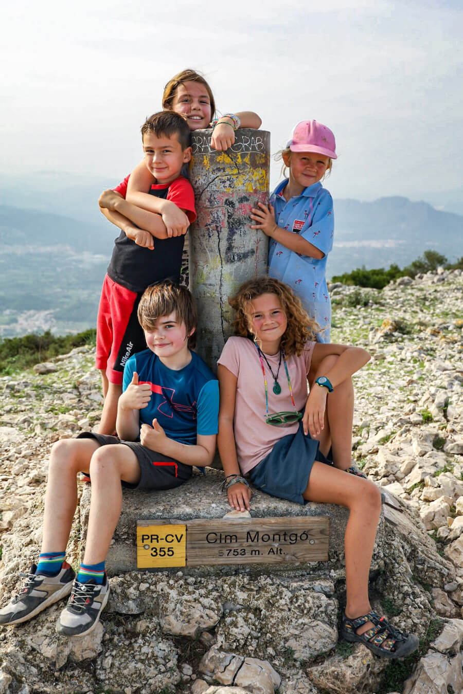 A group of kids stand at the summit marker at 753m on Montgo in the Parque Natural in Javea / Xabia
