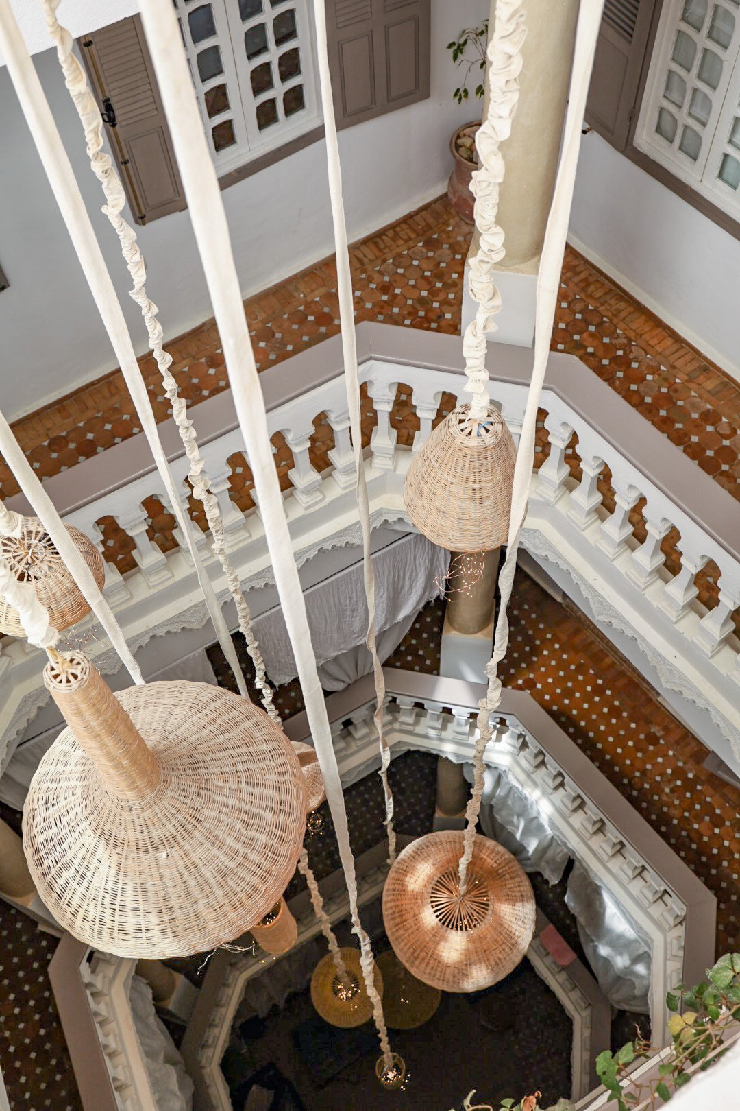 A beautiful riad in Essaouira, Morocco with wicker light fittings hanging across the floors of the riad