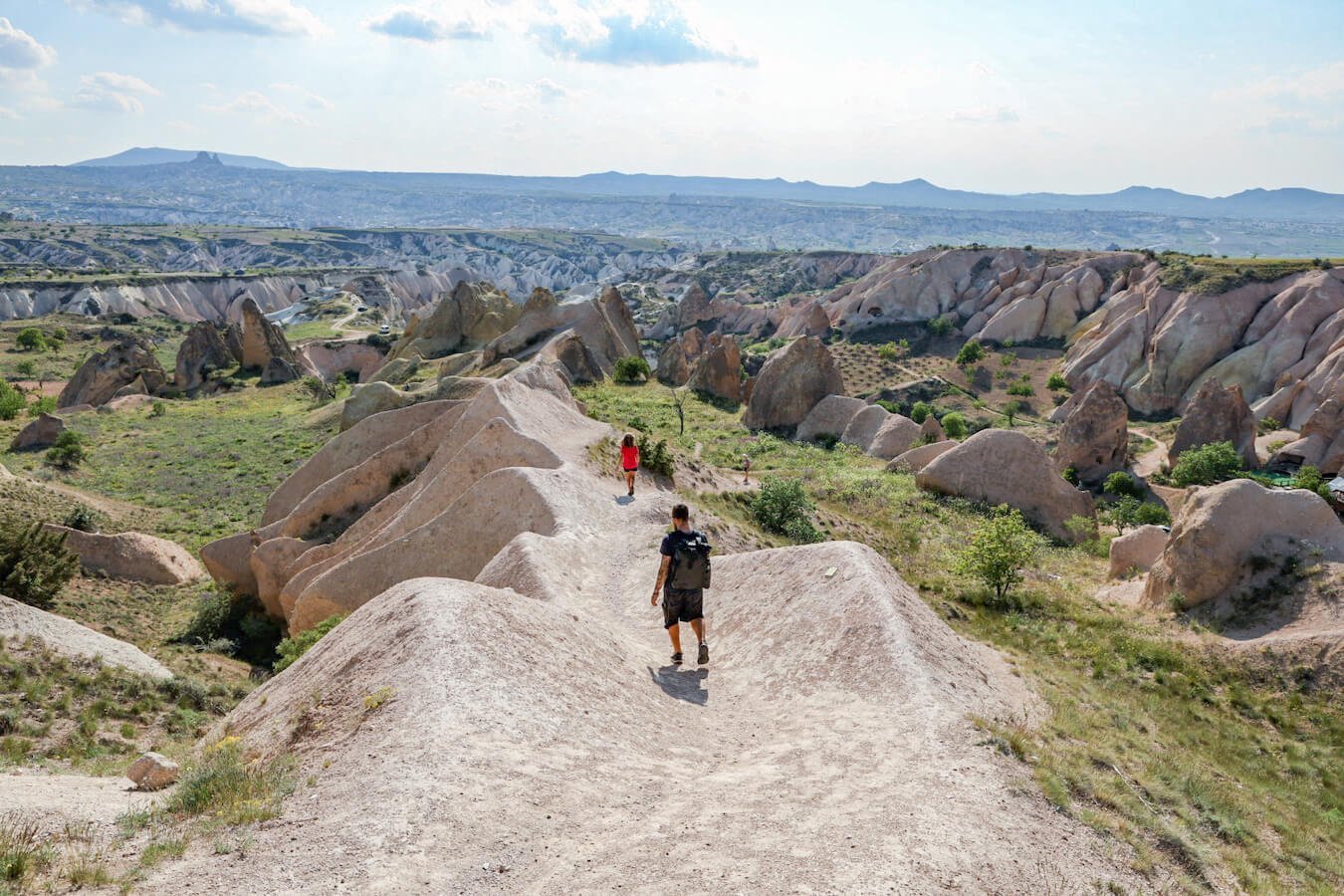 A father and child walk a path towards the rose and red valley in Cappadocia
