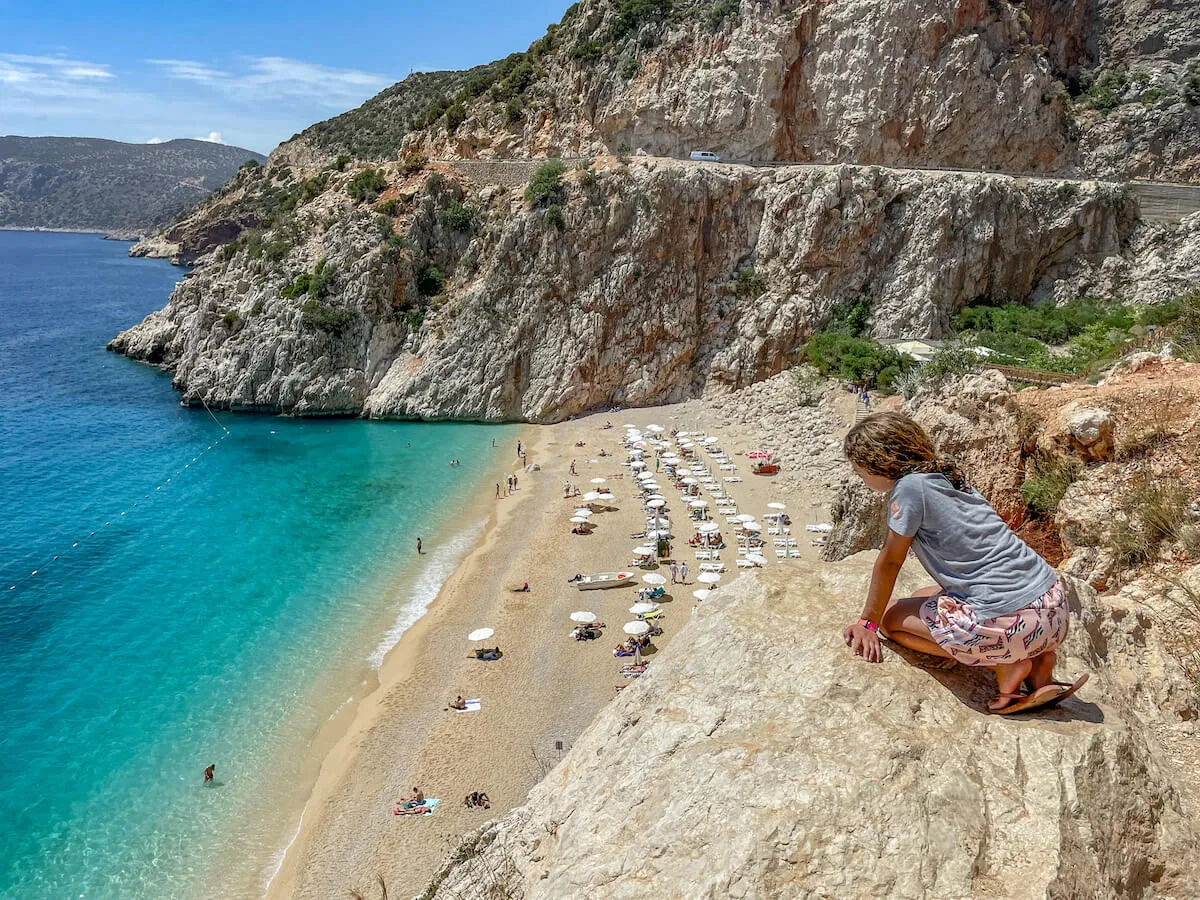 A girl stops to look at Kaputas beach from above on the Mediterranean ocean in Turkey.