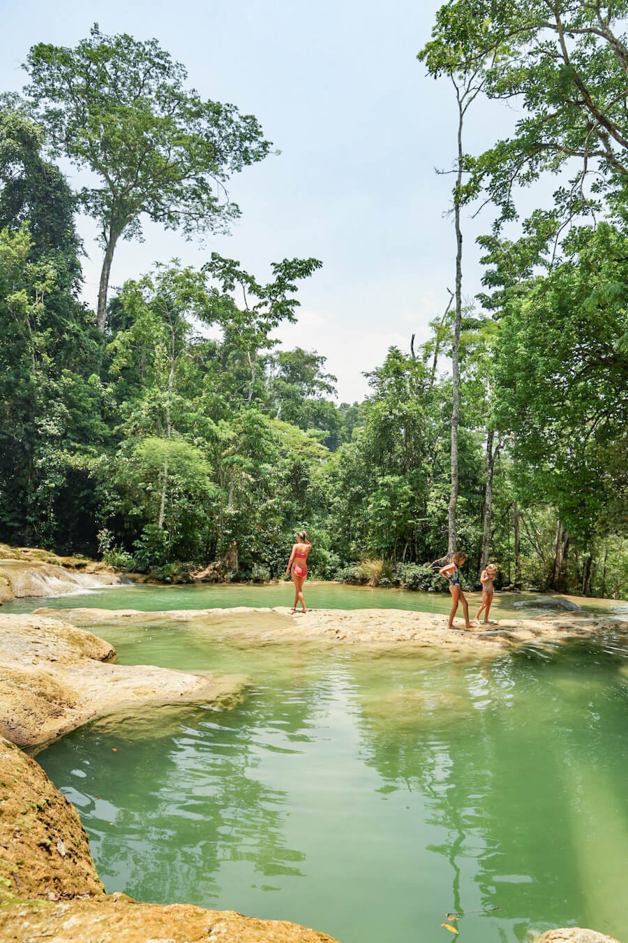 A mother and her daughters walking over a natural rock formation, between two fresh water pools, at Roberto Barrios Cascades.