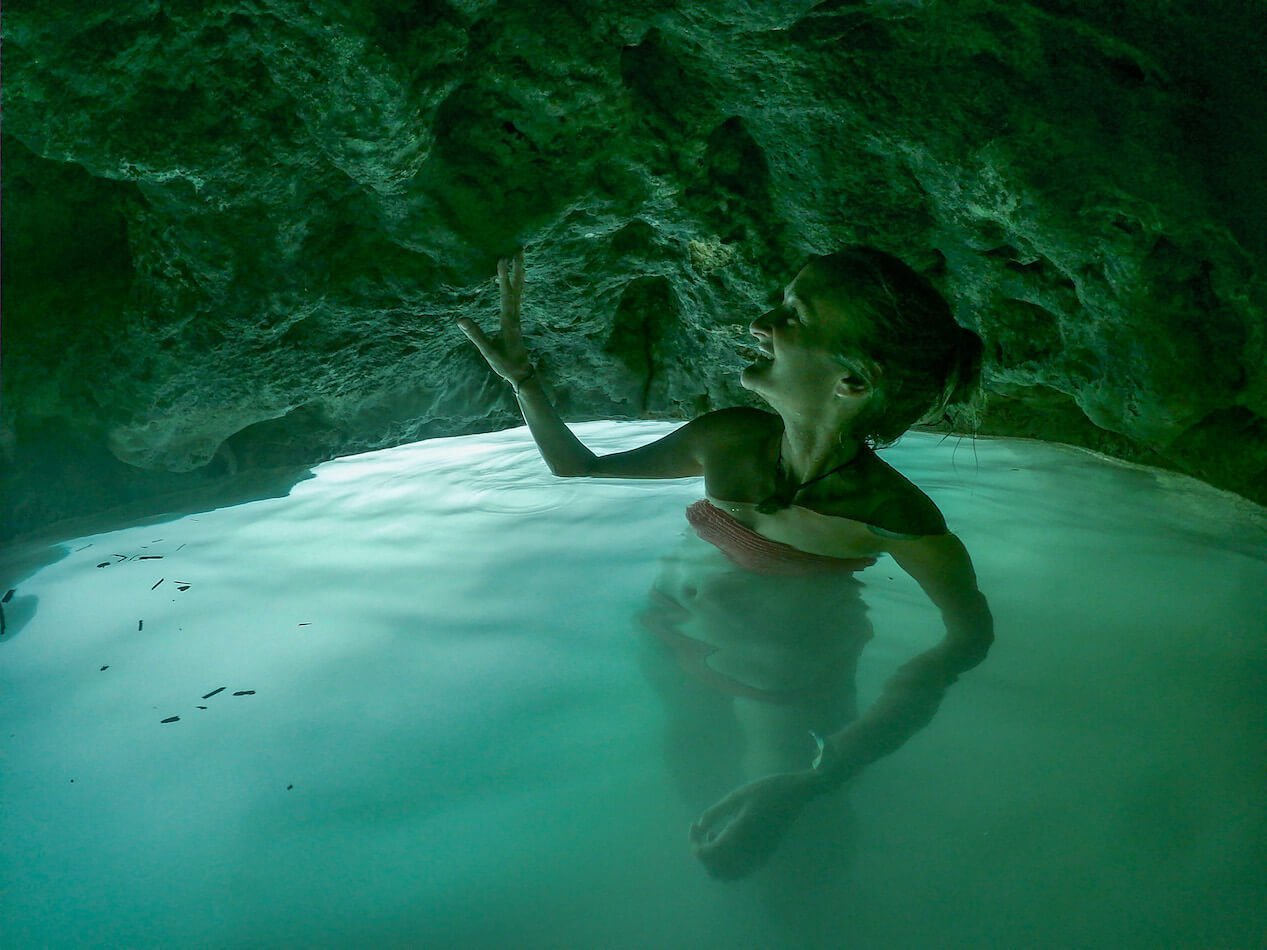 A lady standing inside a hidden water cave, at Roberto Barrios Cascadas. 
