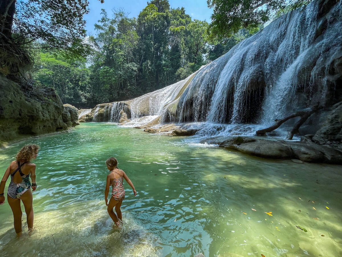Two girls swim in front of one of the biggest waterfalls at Roberto Barrios Cascadas in Palenque