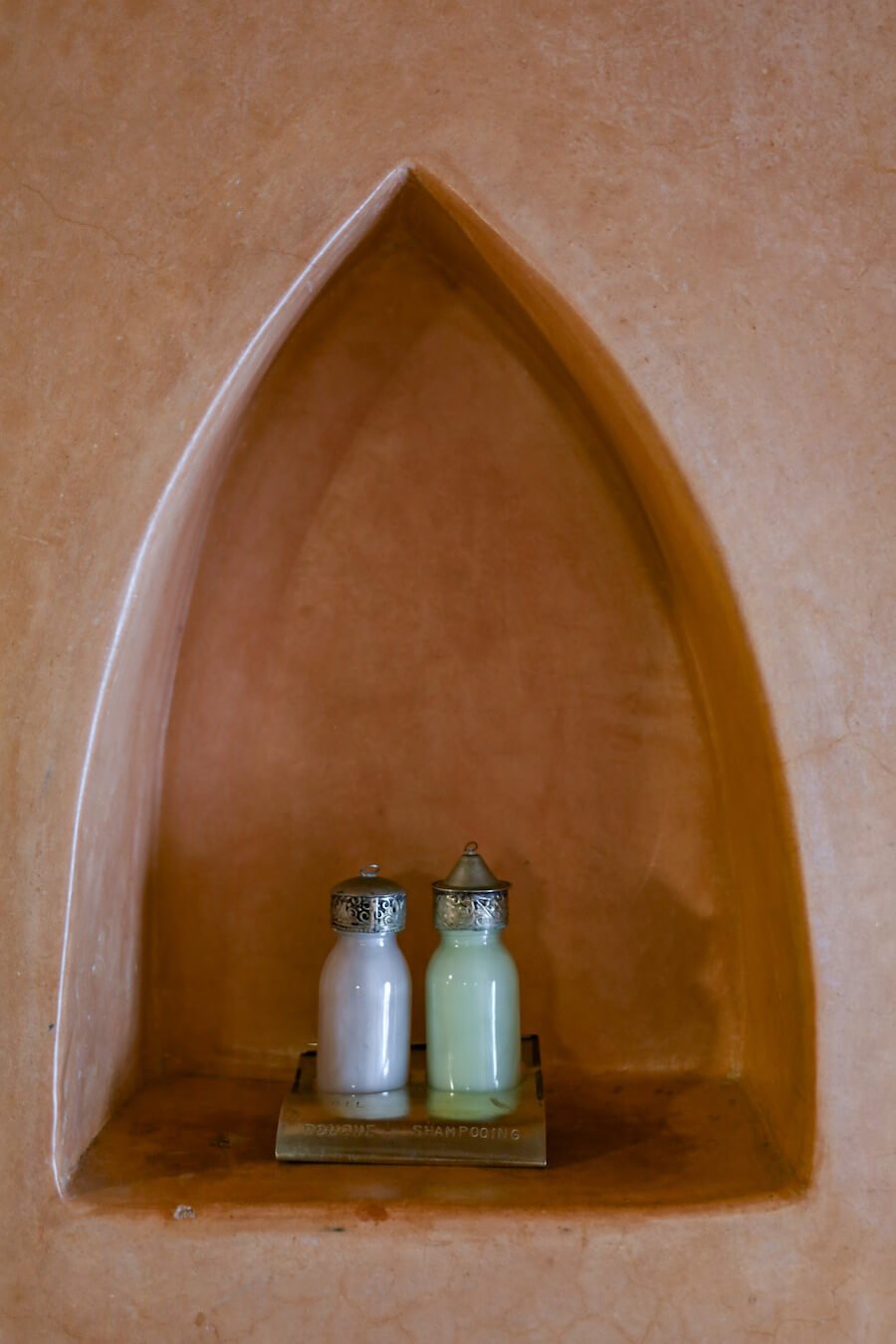 Glass jars filled with shampoo and shower gel sit in the bathroom nook at Ryad Watier in Essaouira - sustainable travel solutions.
