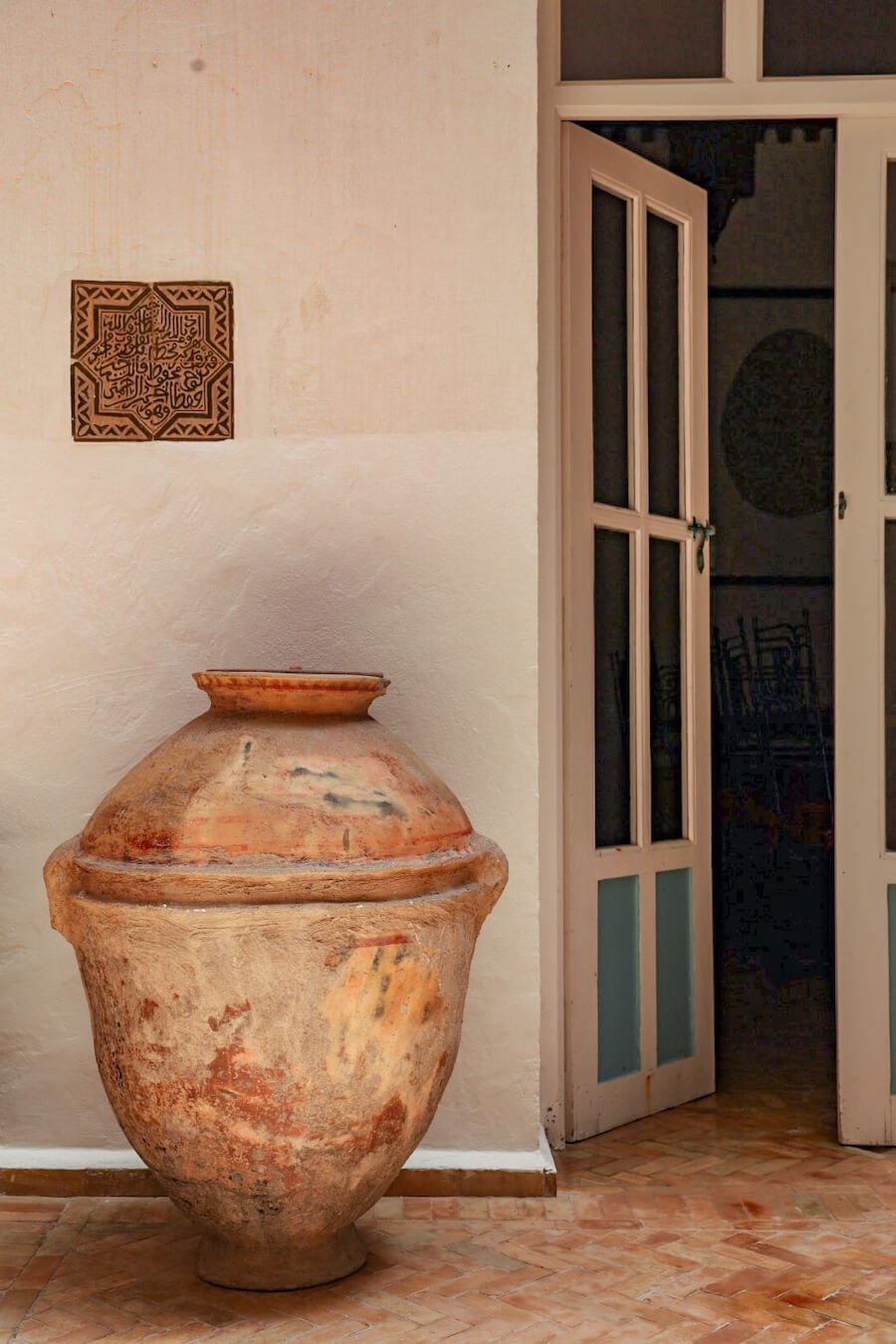 Large terracotta pot in a riad in Morocco with Arabic tiled inlayed on the wall