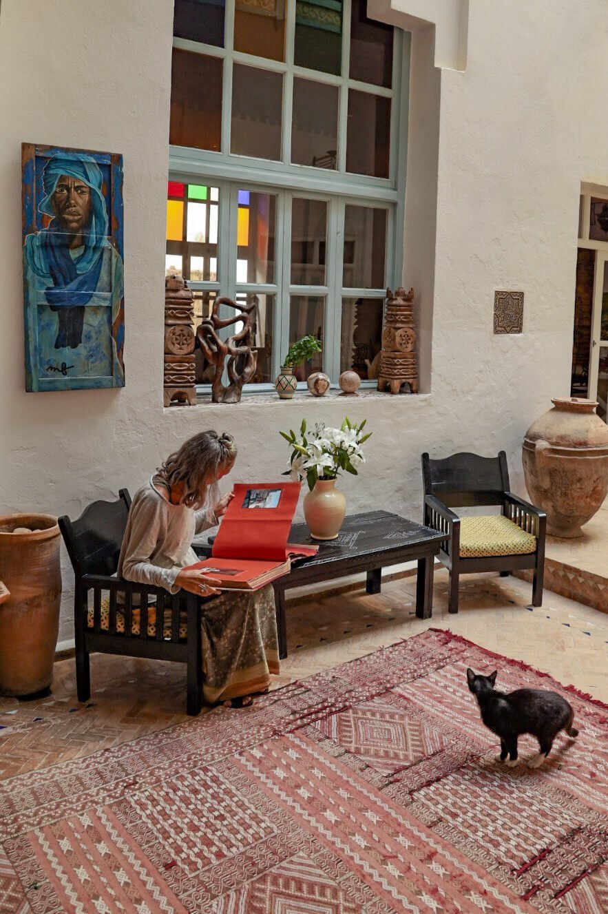 lady reads the story of Ryad Watier in Essaouira Morocco while sitting in a riad courtyard.