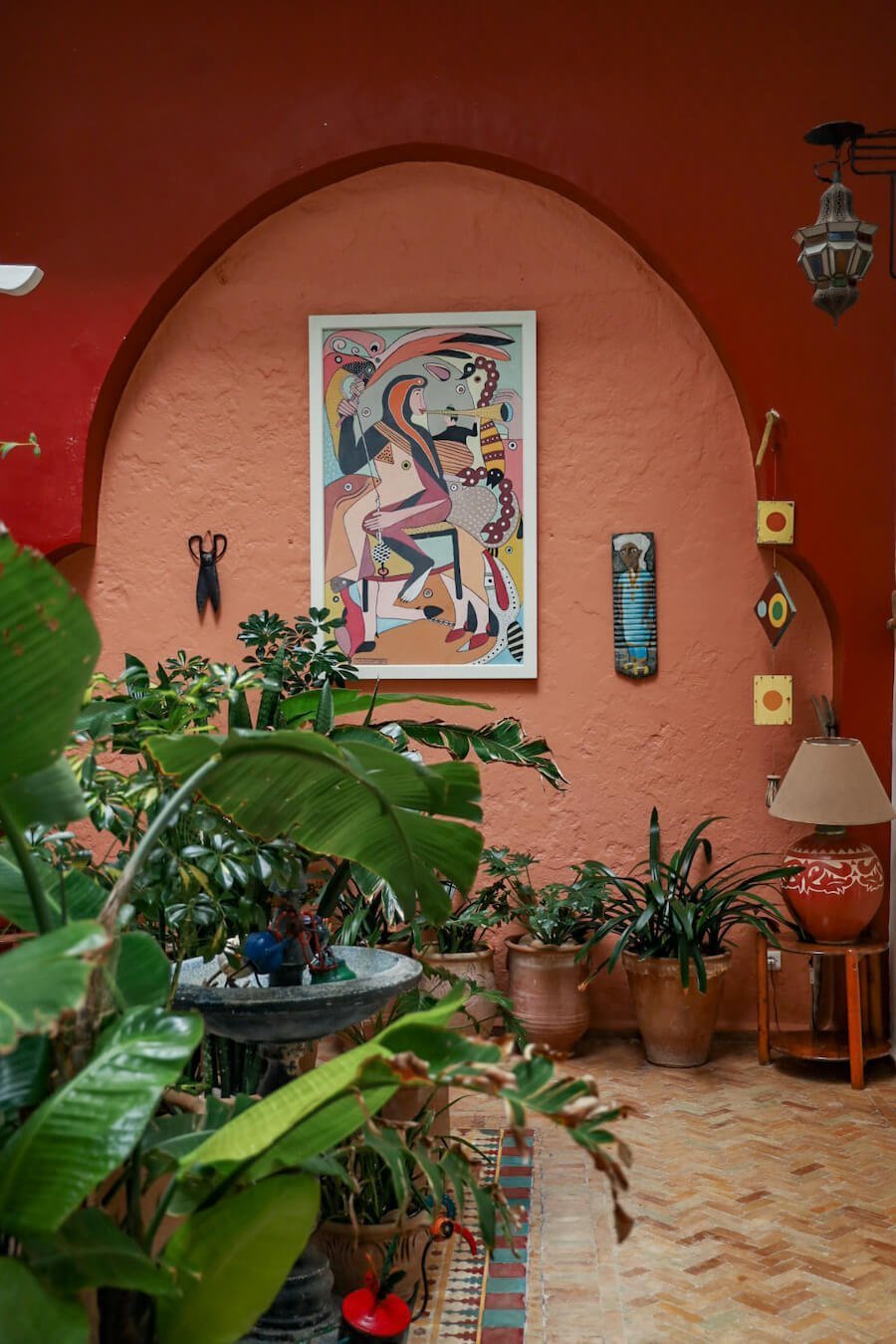 The unique paintings and interior decor of the Ryad Watier in Essaouira.  The green plants against the terracotta coloured walls are very typical of Moroccan design.