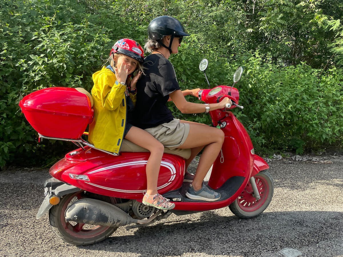 A mother and kid ride a scooter in Valladolid, Mexico while looking for cenotes.