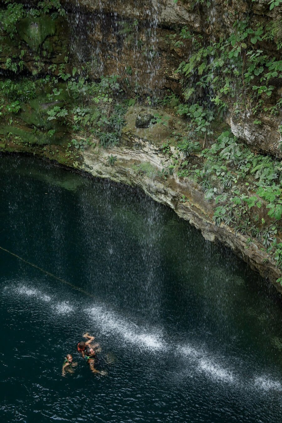 A family swim in the waterfall cascades at Saamal Cenote at  Hacienda Selva Maya in Valladolid.