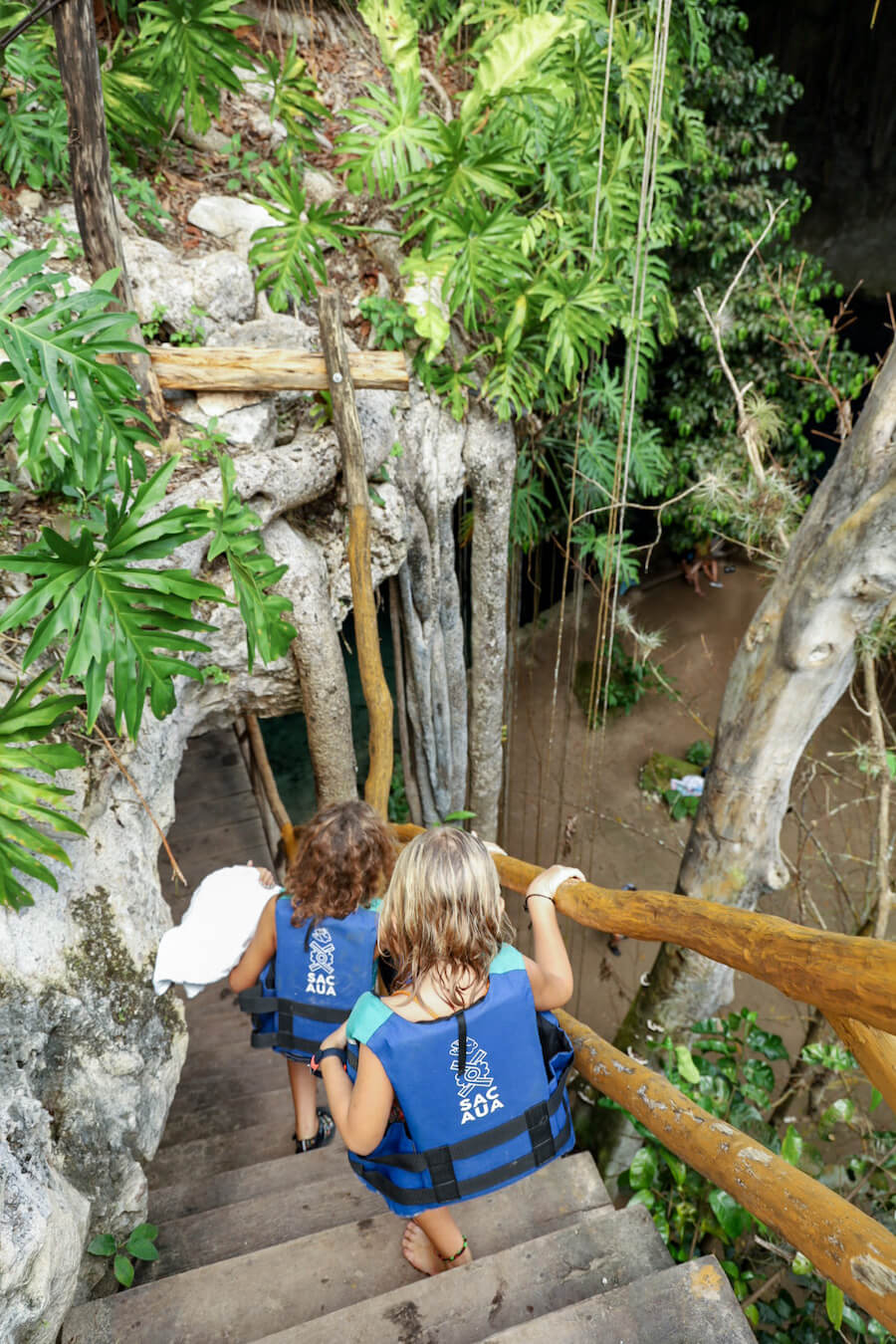 Children wearing life jackets walk down into a cenote in Mexico.