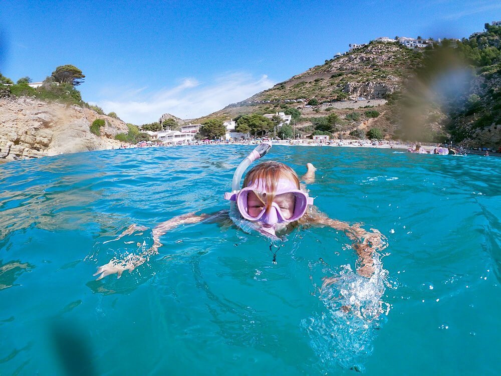 A child snorkels on Granadella beach in Javea Spain