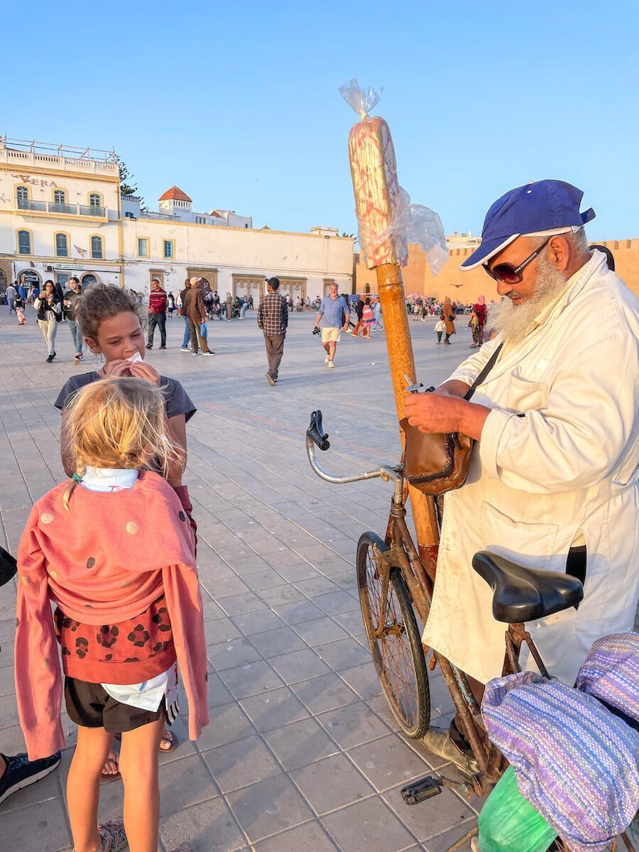 A man sells candy on a long stick in Essaouira square