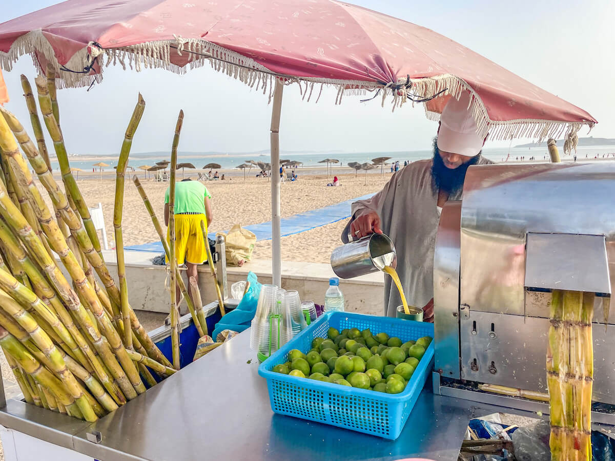 A main makes freshly squeezed cane sugar juice with lime on the beach in Essaouira