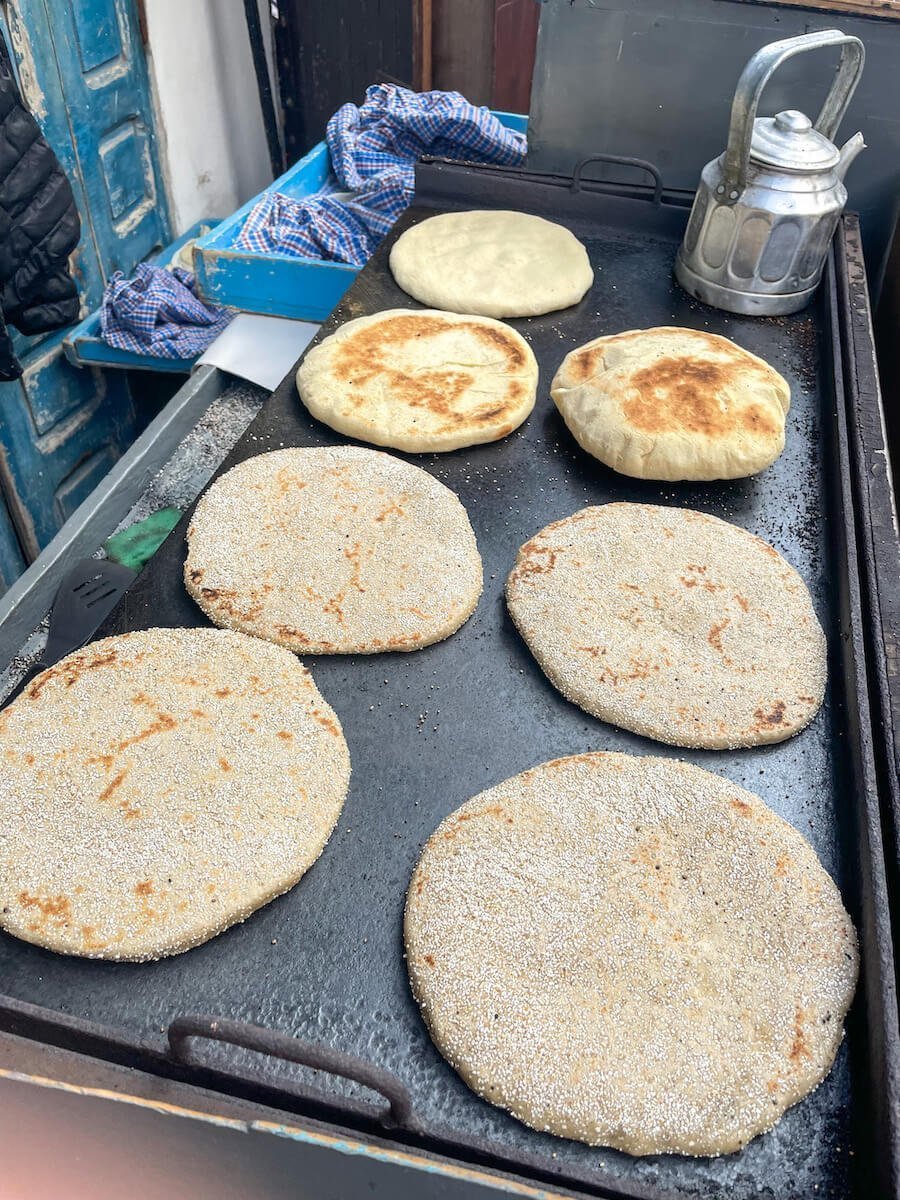 Local Moroccan bread and Harcha bread are cooked on a hot plate in an Essaouira food stall