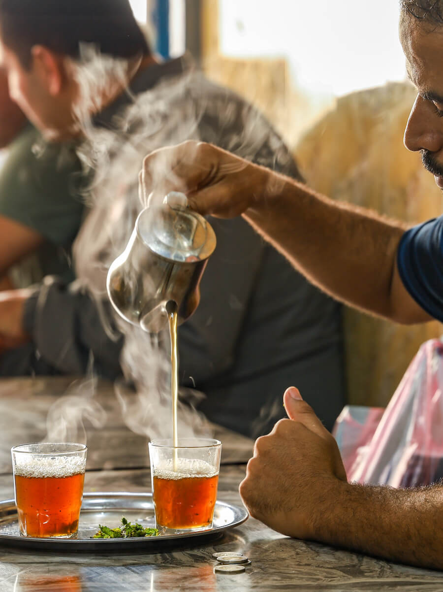 A man pours mint tea in a street food stall kitchen in Essaouira medina