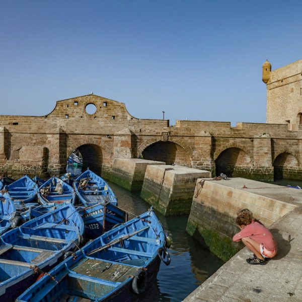 Children look at the fishing boats in Essaouira - one of the most popular things to do in the windy city in Morocco.