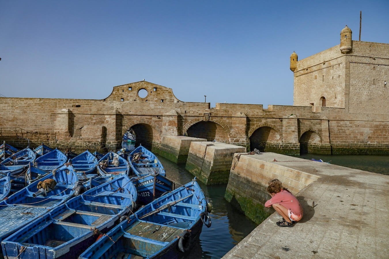 Children look at the fishing boats in Essaouira - one of the most popular things to do in the windy city in Morocco.