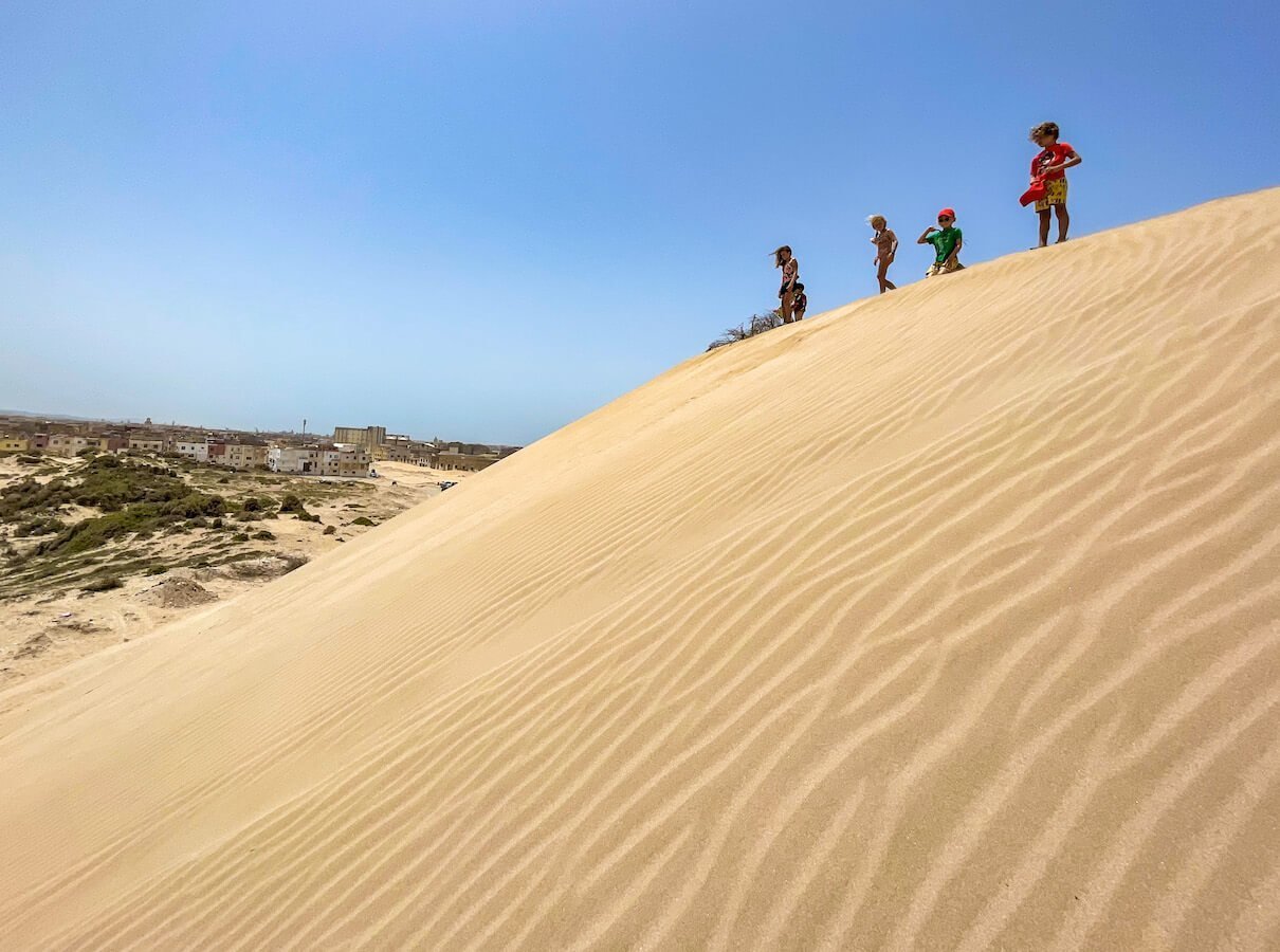 Kids stand at the top of the sand dunes in Essaouira at the Northern beach - one of the best things to do