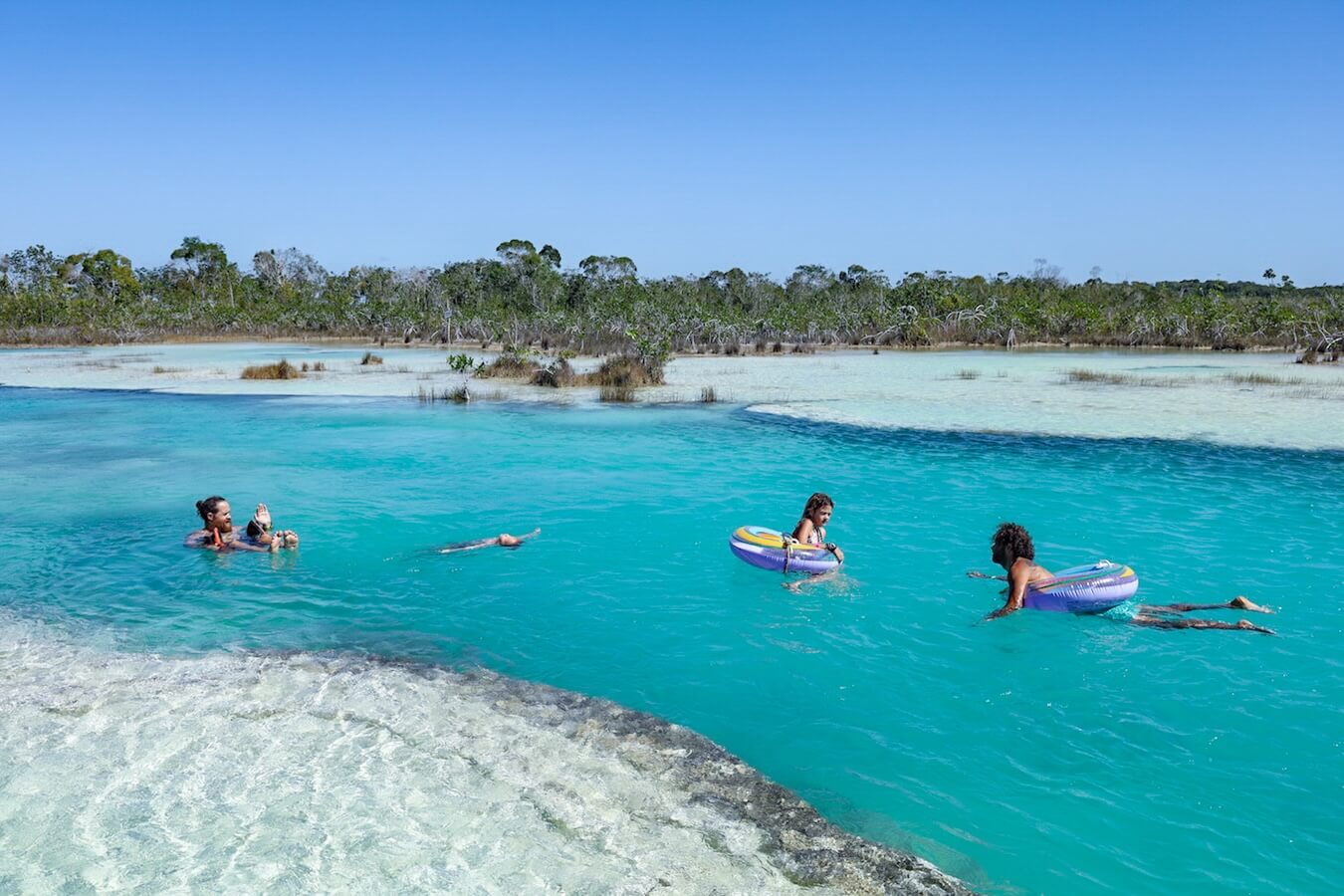 A group float down Los Rapidos on floating tubes next to stromatolites - a must do on a list of things to do in Bacalar Mexico