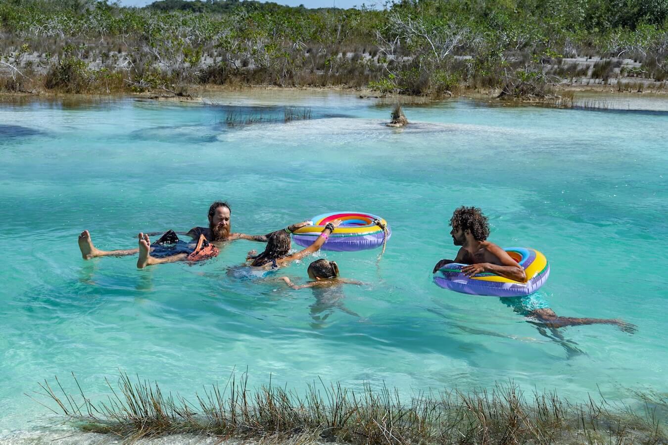 A group float down electric blue current at Los Rapidos on floating tubes - a must do on a list of things to do in Bacalar Mexico