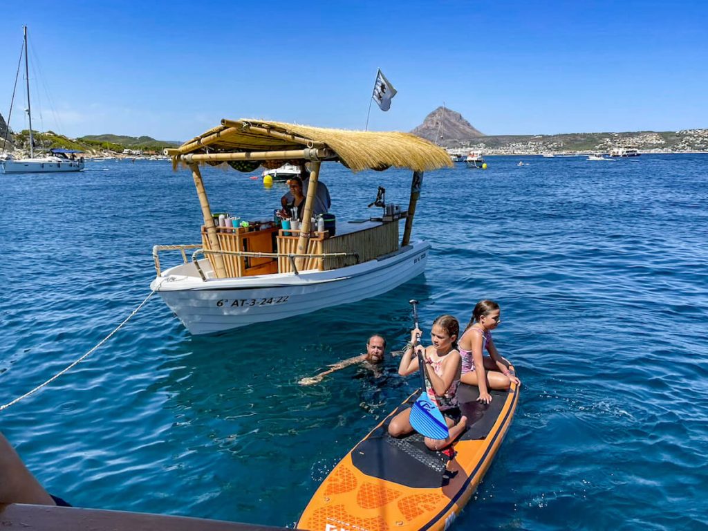 A family paddle board in the water while waiting for a cocktail from the boat and tiki bar in Javea - one of the fun things to do in Javea.