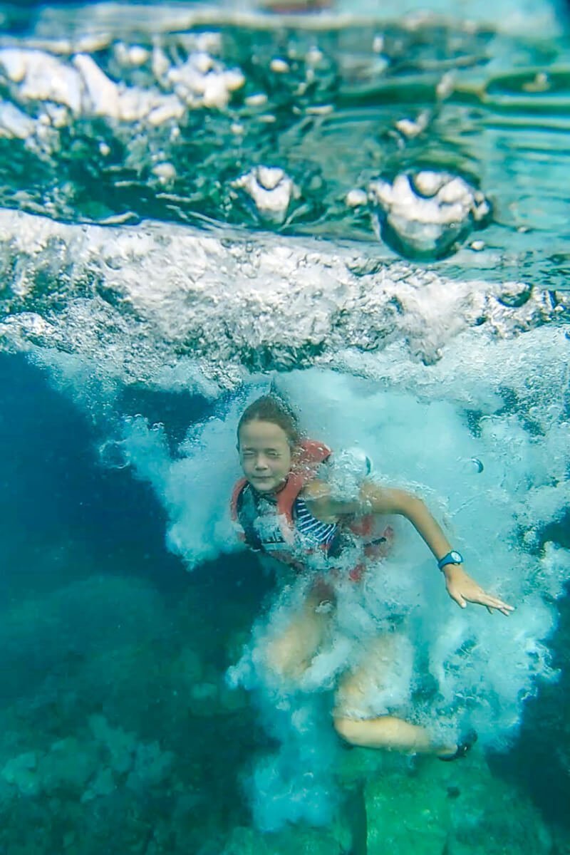 A child photographed jumping into the clear water at Cala Tango in Javea - this is one of the fun things to do when on holiday in Javea.