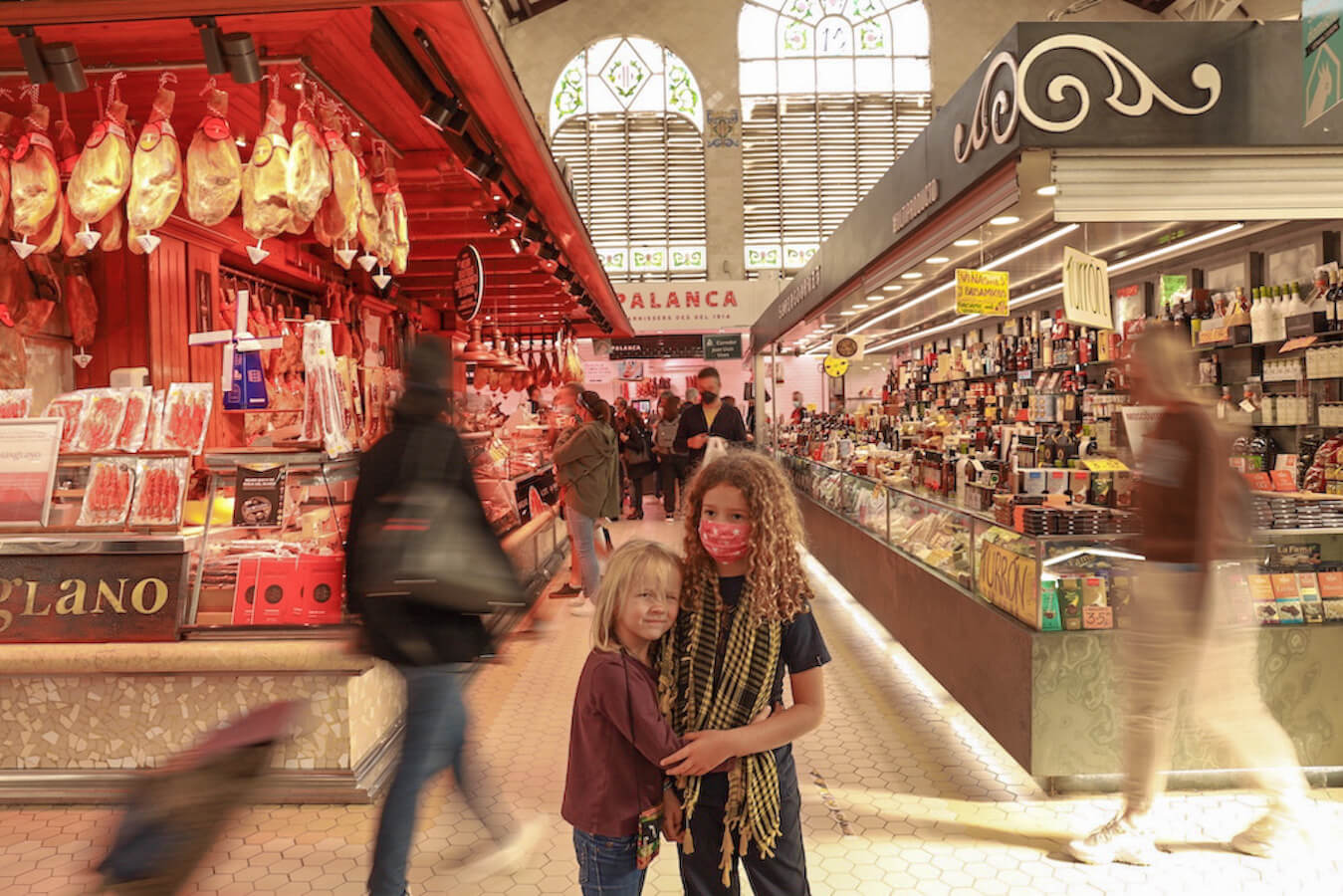 Kids stand in the food market in Valencia on a day trip from Javea.