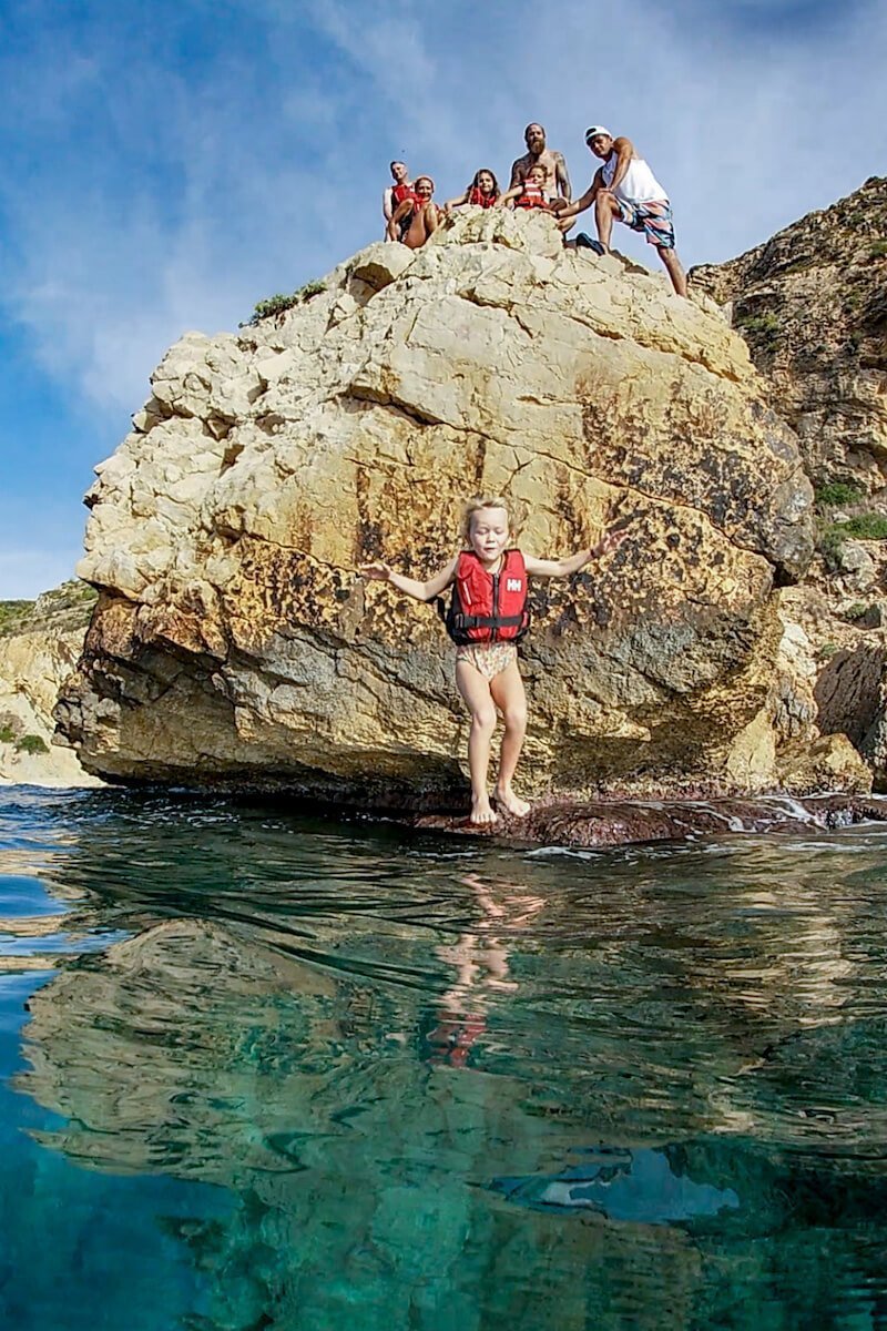 A child mid jump while cliff jumping in Javea / Xabia