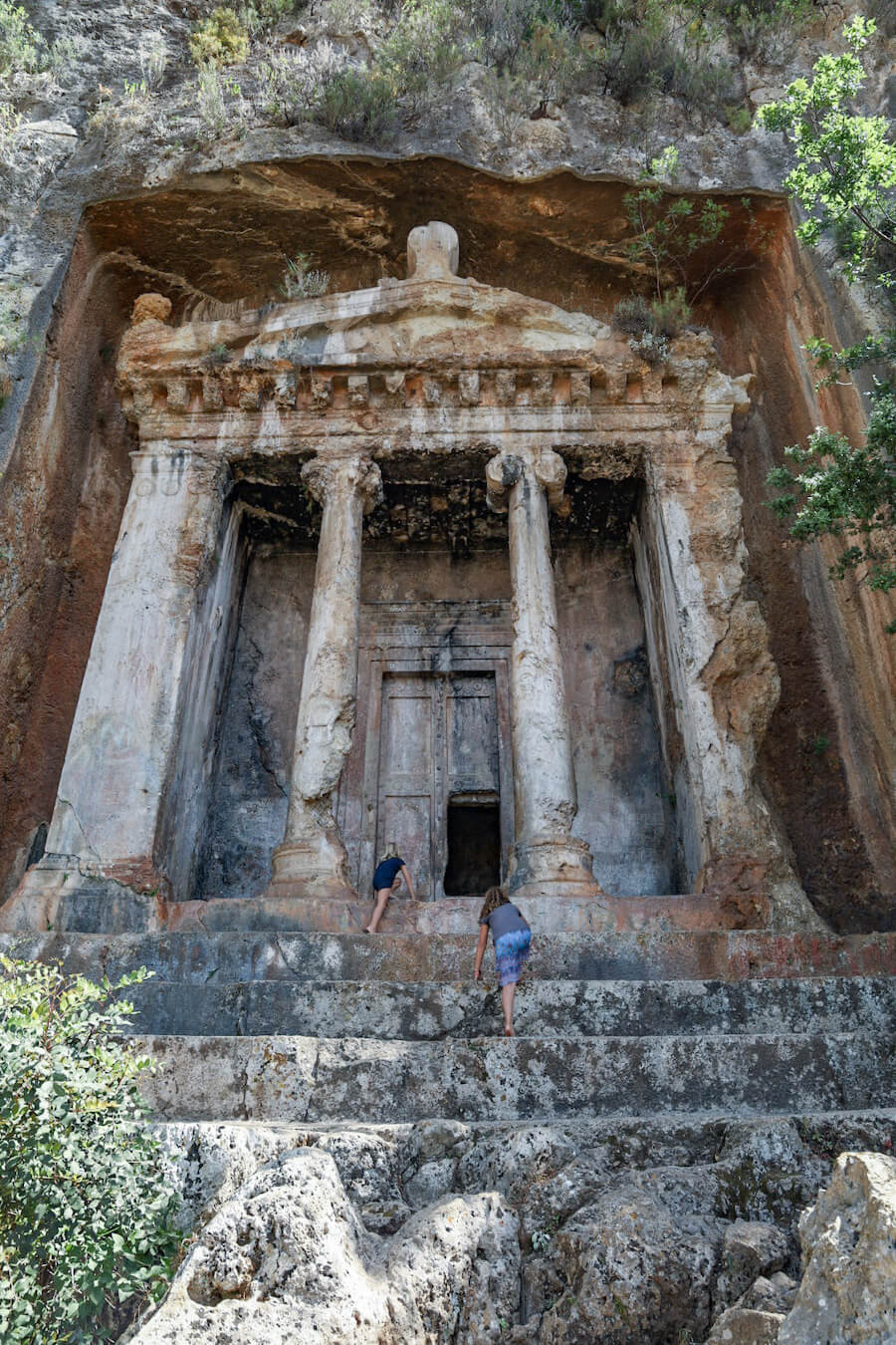 Children climb the steps of the Amyntas rock tombs in Fethiye - as they explore nearby things to do from Kas.