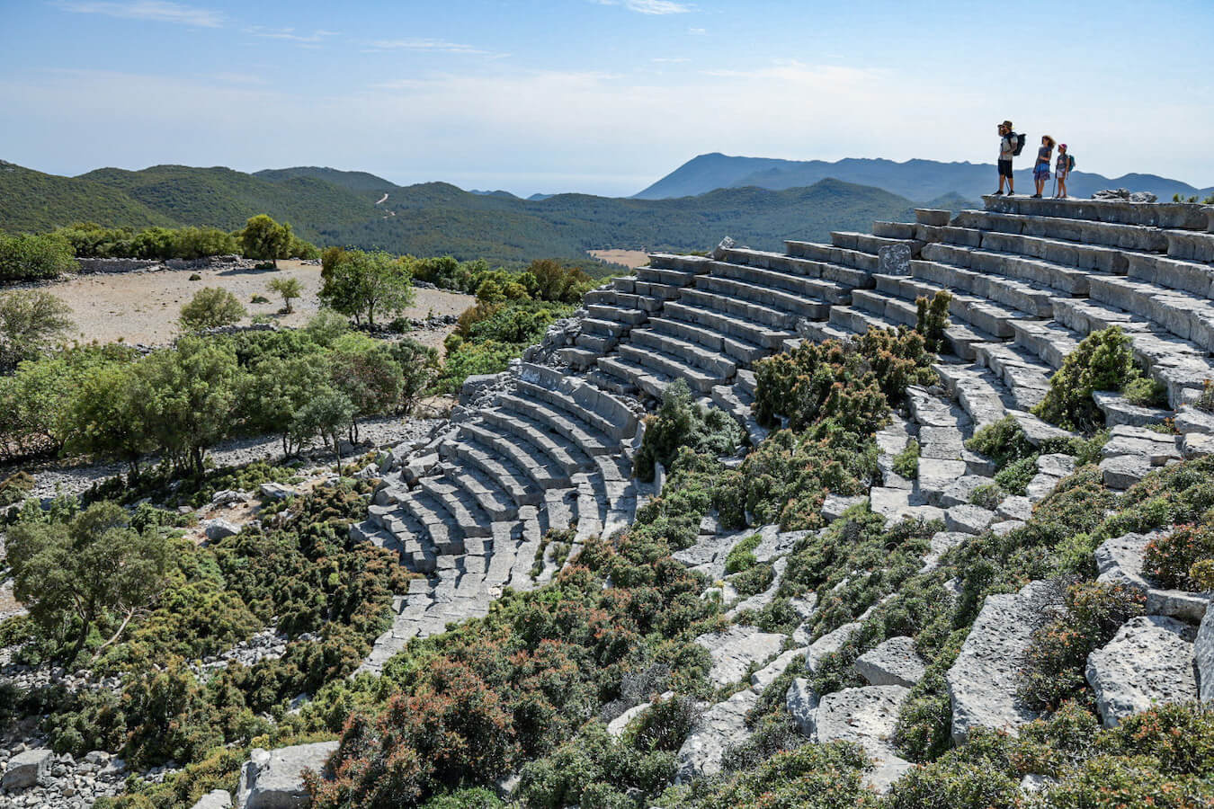 Father and children stand at the top of the theatre at Kyaneai Ören Yeri ruins - as they explore things to do in Kas.