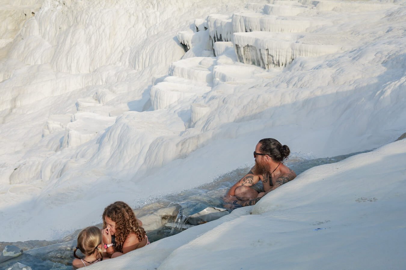 A family swim in the warm thermal spring of the travertine terraces in Pamukkale - this is one of the most Instagrammable places to visit and things to do in Turkey.