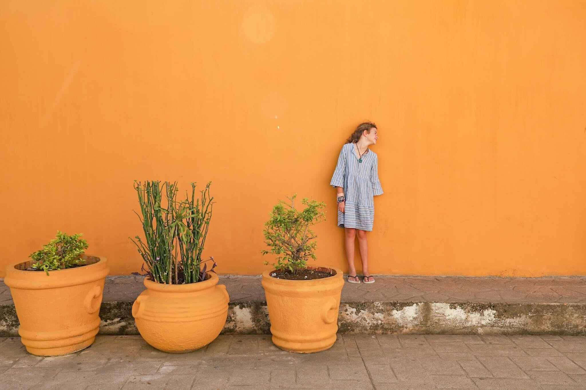 A young girl standing in front of a yellow wall on Calzada de los Frailes in Valladolid