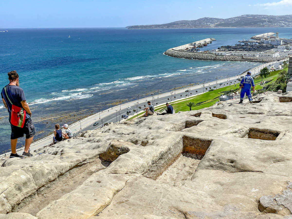 A family site seeing at the Phoenician Tombs overlooking the port at Tangier - one of the top things to do on a Tangier itinerary.
